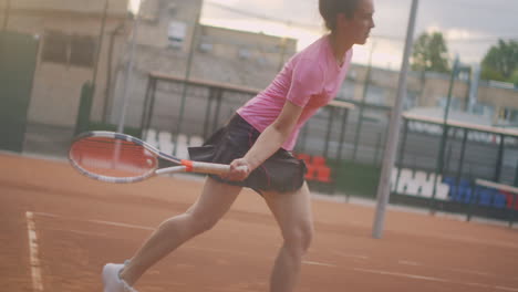 Professional-equipped-female-beating-hard-the-tennis-ball-with-tennis-racquet.-Female-tennis-player-in-action-during-game.-She-is-wearing-unbranded-sport-clothes.